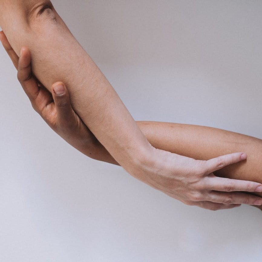 crop hands of anonymous multiethnic couple touching hands in light studio