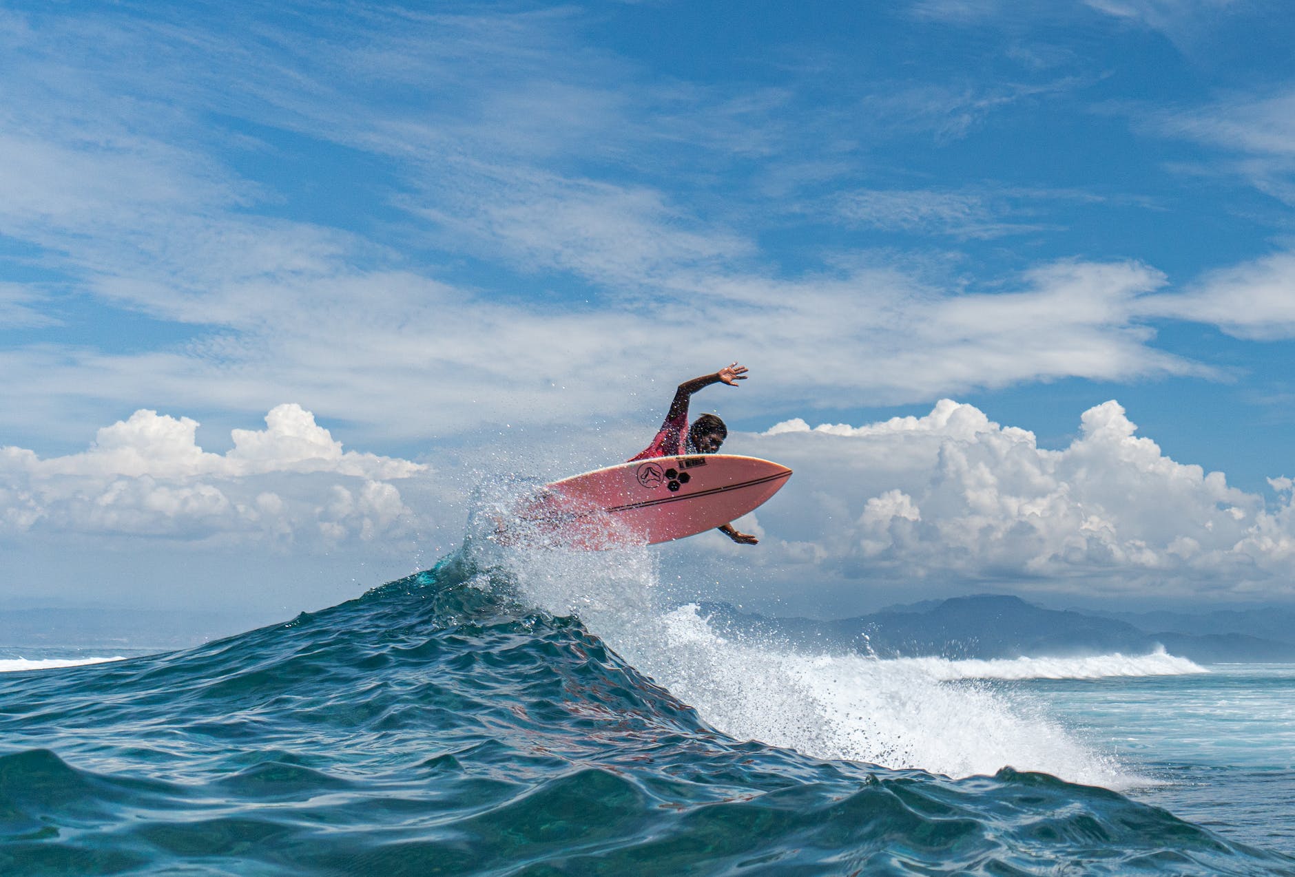 black surfer practicing extreme sport above ocean wave